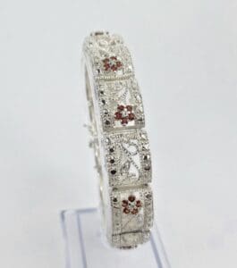 Ornate silver bracelet with red gemstones.