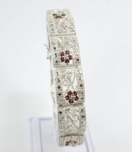 Ornate silver bracelet with red gemstones.
