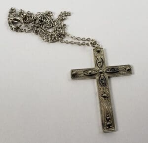 Silver cross pendant with intricate chain design.