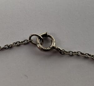 Silver chain with circular clasp on grey.