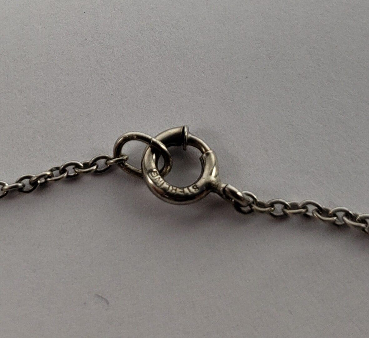 Silver chain with circular clasp on grey.
