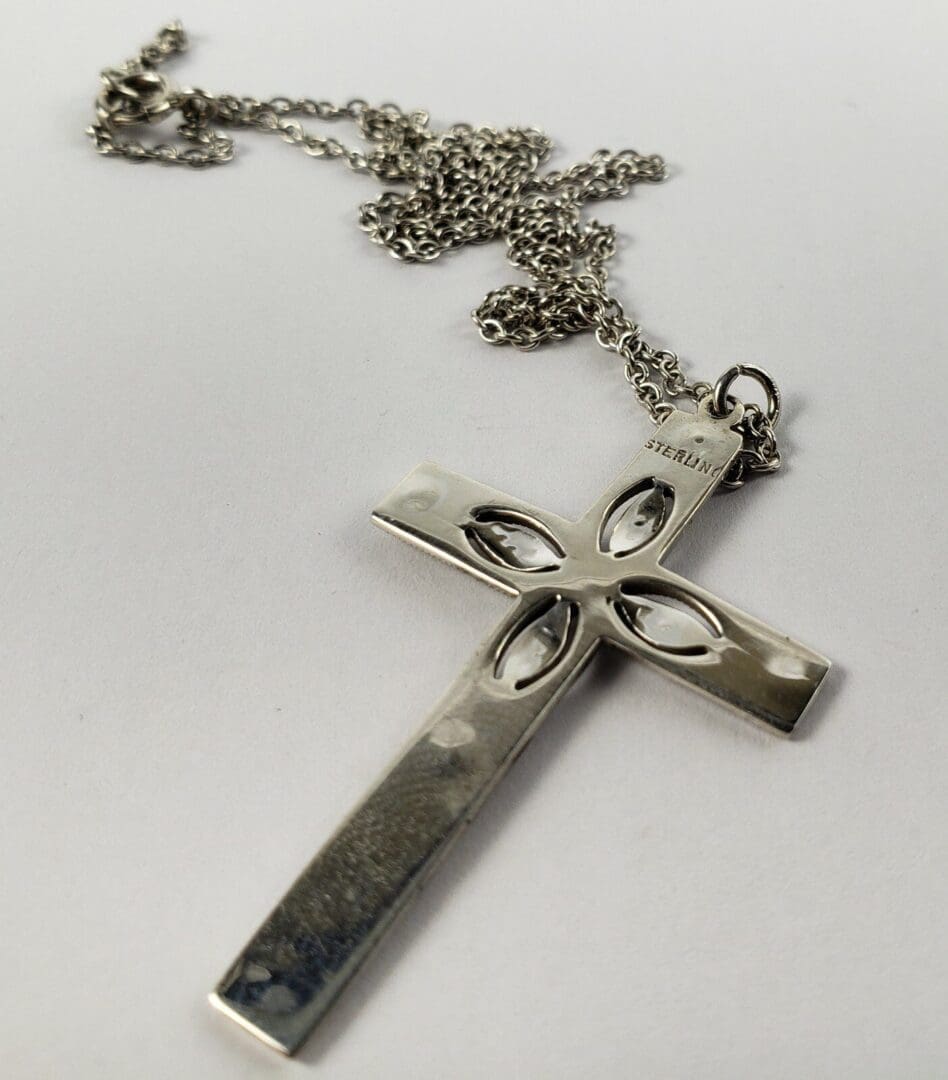 Silver cross pendant with decorative chain.
