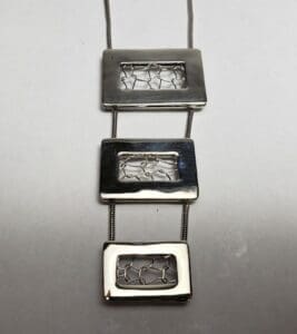 Geometric silver pendant with rectangular designs.