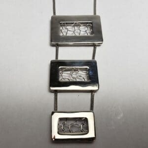 Geometric silver pendant with rectangular designs.