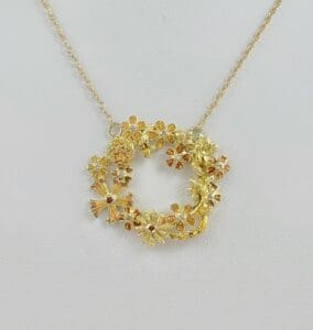 Gold floral necklace on white background.