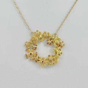 Gold floral necklace on white background.