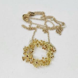 Gold floral wreath necklace on white background.