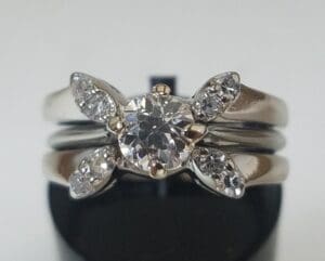 Diamond ring with floral design on stand.