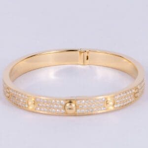 Gold bracelet with diamond accents and screws.