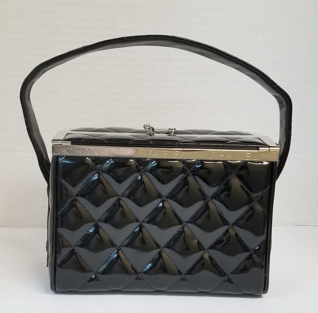 Black quilted handbag with top handle.