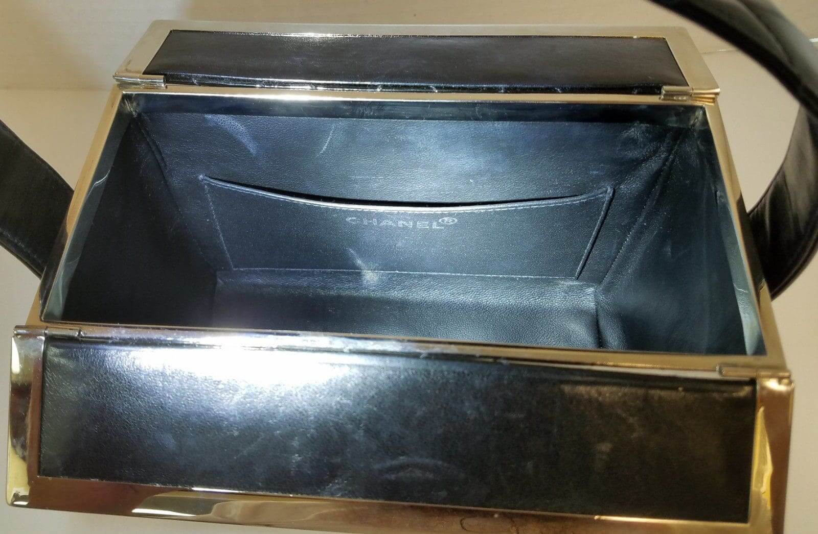 Open black leather handbag with metal frame.