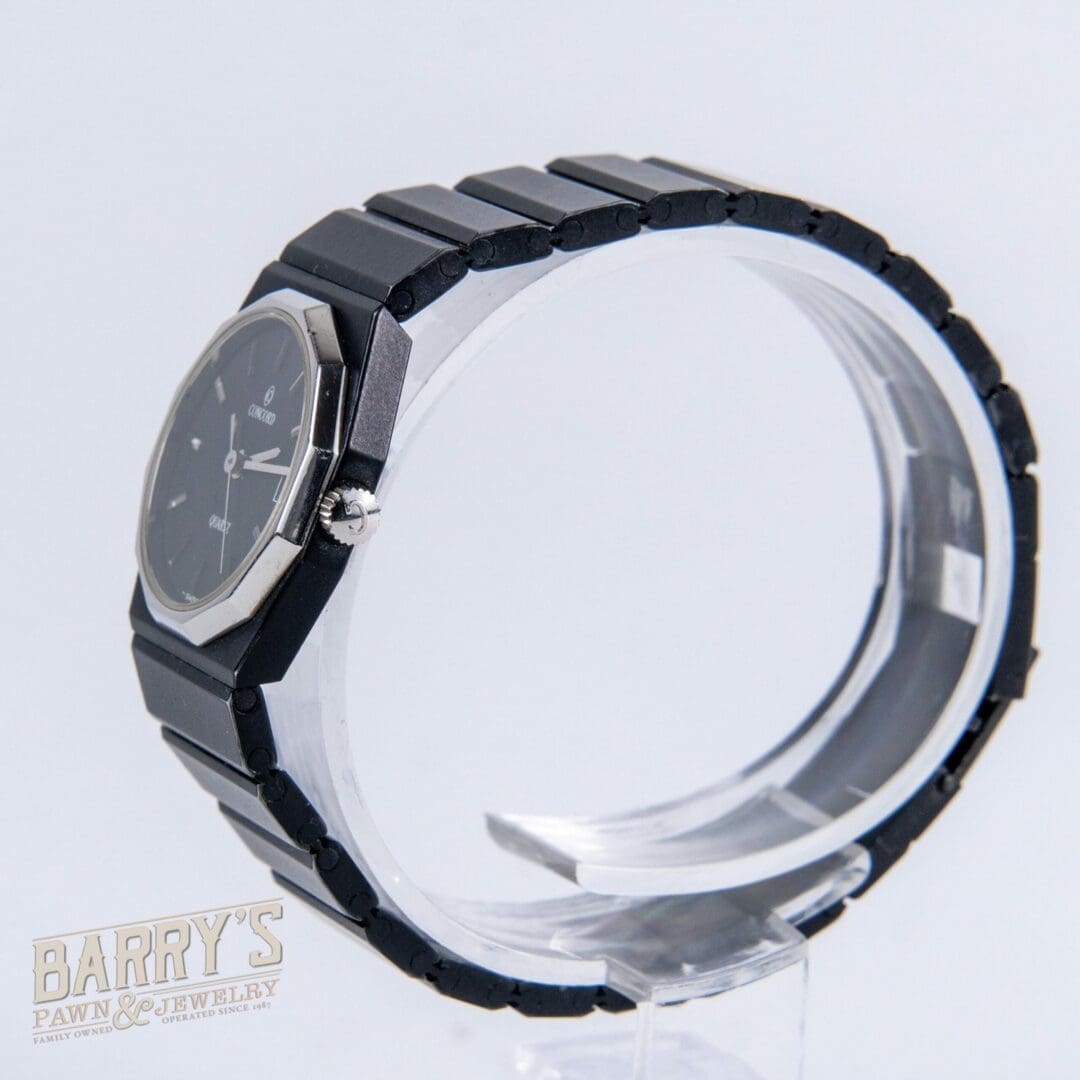 Black wristwatch displayed on transparent stand.