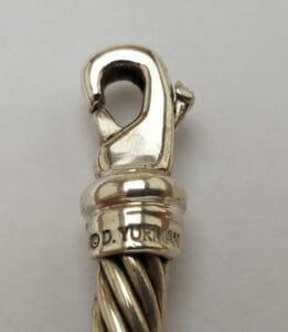 Silver jewelry clasp with engraved brand name.