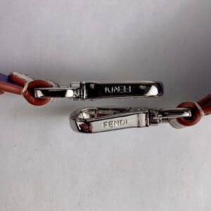 Fendi engraved metal clasps on leather strap.