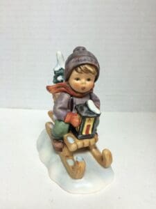 Child figurine sledding with lantern.