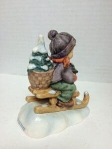 Child figurine on sled with tree.