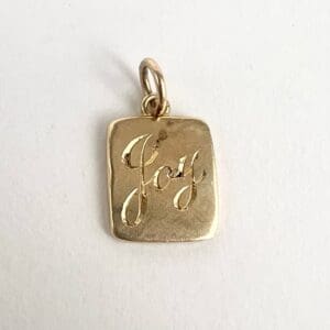 Gold pendant with "Joy" engraving.