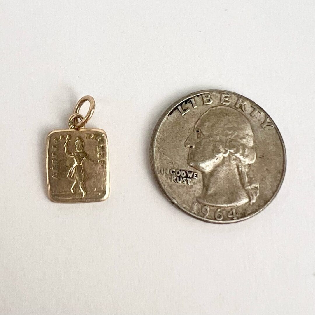 Gold pendant beside a 1964 quarter coin.