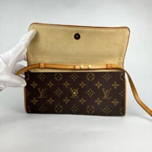 Open designer wallet with gloved hand holding.