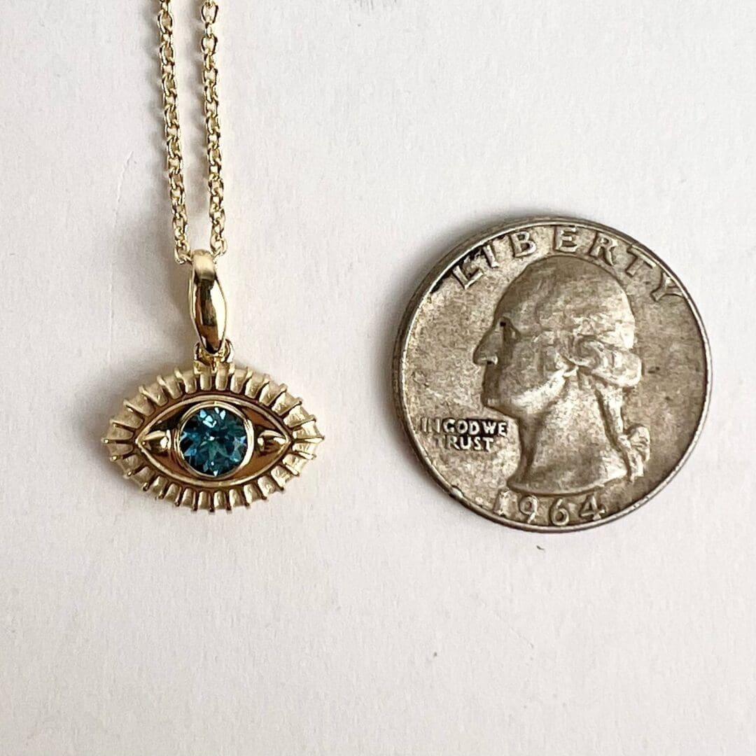 Gold necklace with eye pendant and coin.
