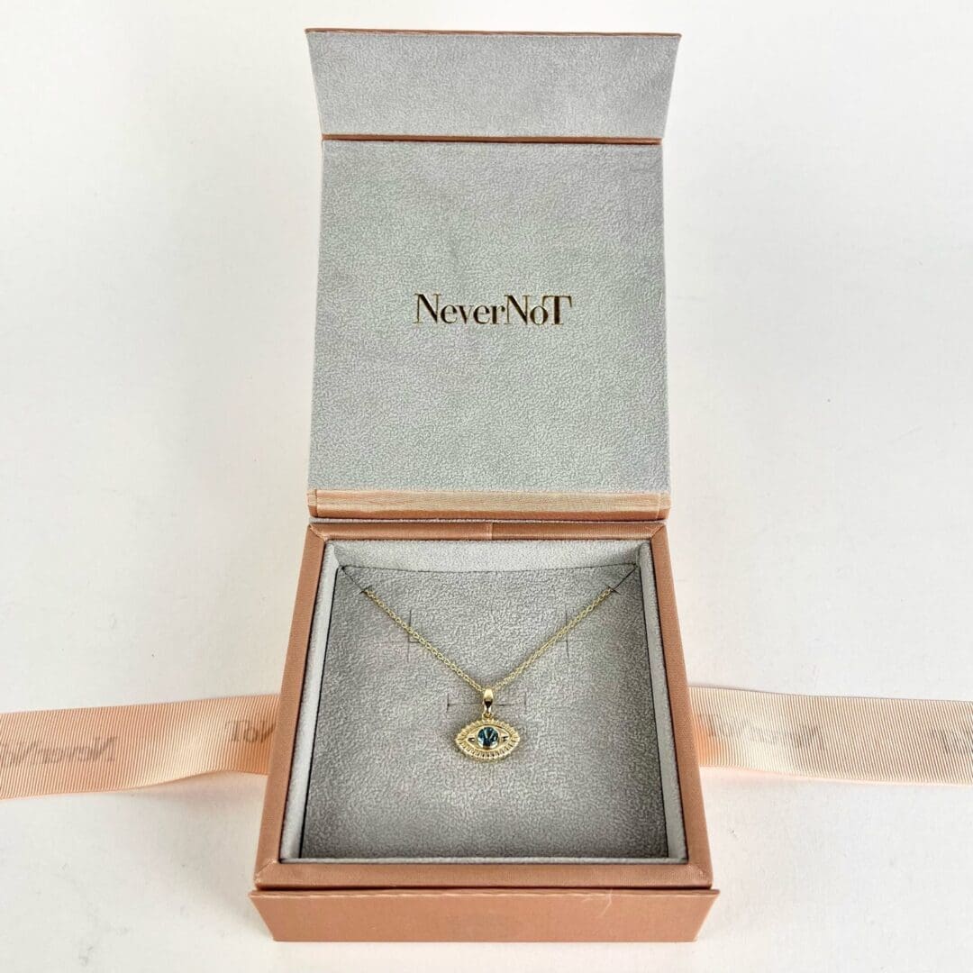 Gold necklace with eye pendant in box.