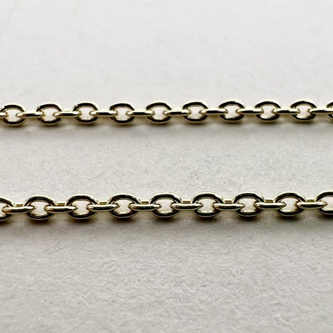 Two parallel gold chains on white background.