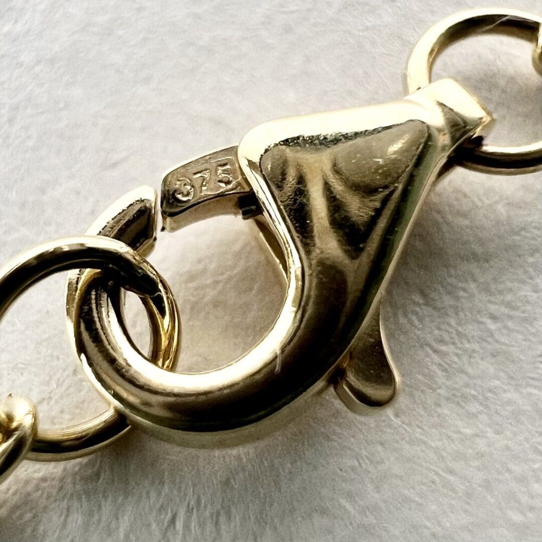 Gold lobster clasp with engraved markings.
