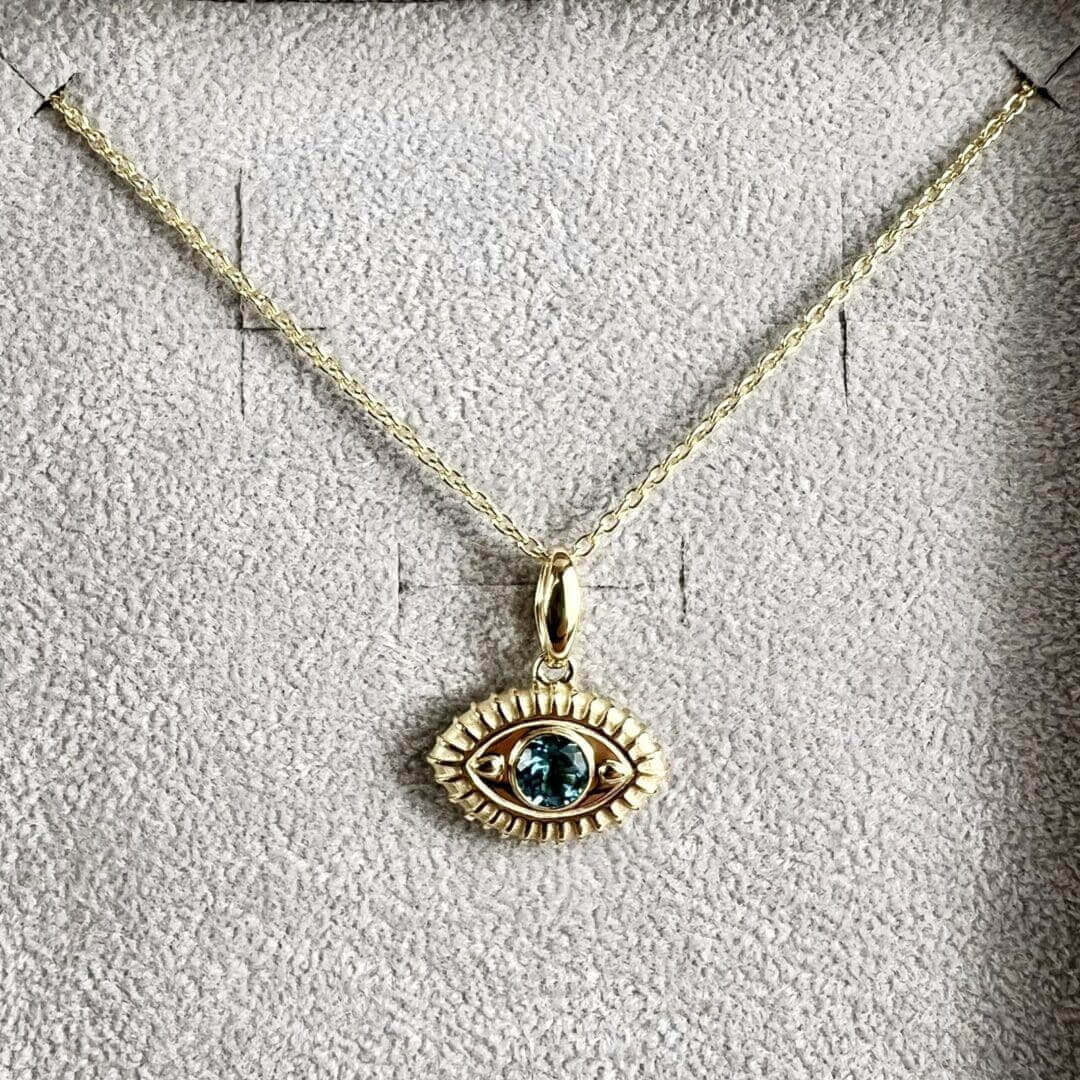 Gold necklace with eye-shaped pendant.