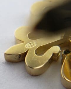 Gold clover-shaped pendant with engraved markings.
