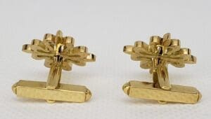 Gold cufflinks with intricate floral design.