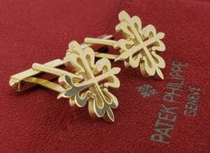 Gold cufflinks on red Patek Philippe fabric.