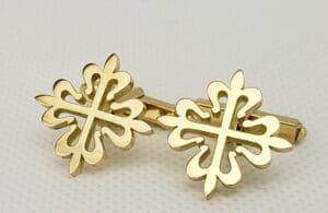 Gold cross-shaped cufflinks on white background.