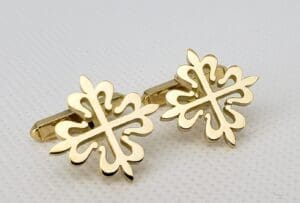 Gold ornate cross-shaped cufflinks on display.