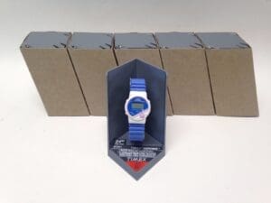 Blue digital watch with packaging boxes behind.
