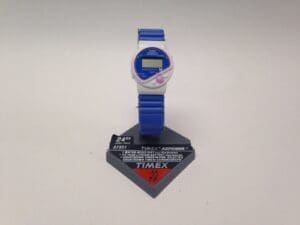 Blue Timex digital wristwatch on display stand.