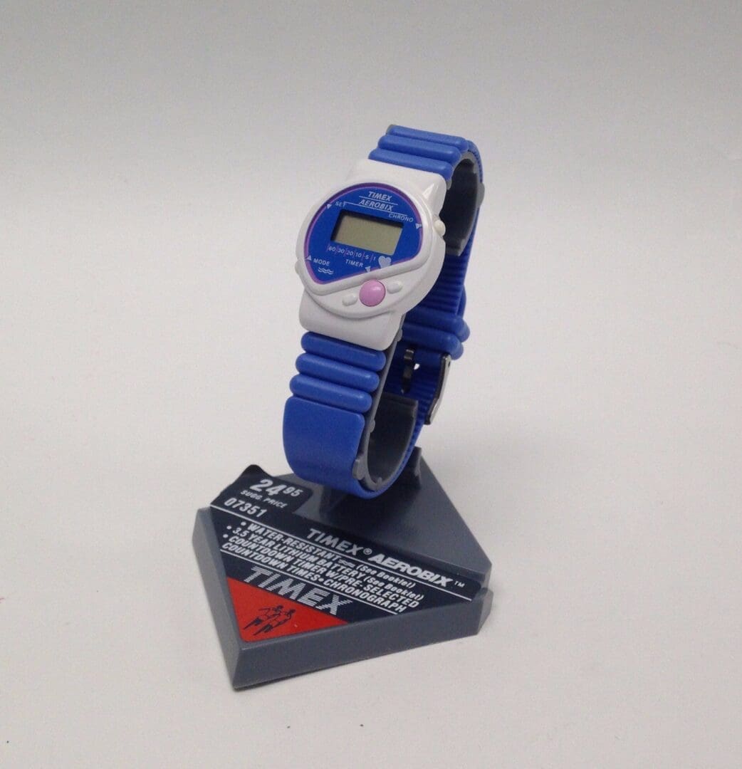 Blue digital watch on display stand.