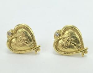 Gold heart-shaped earrings with cupid design.
