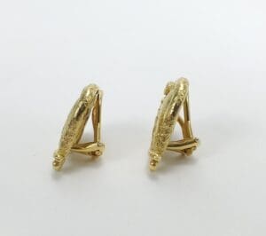 Gold textured clip-on earrings on display.