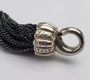 Silver necklace clasp with engraved text details.