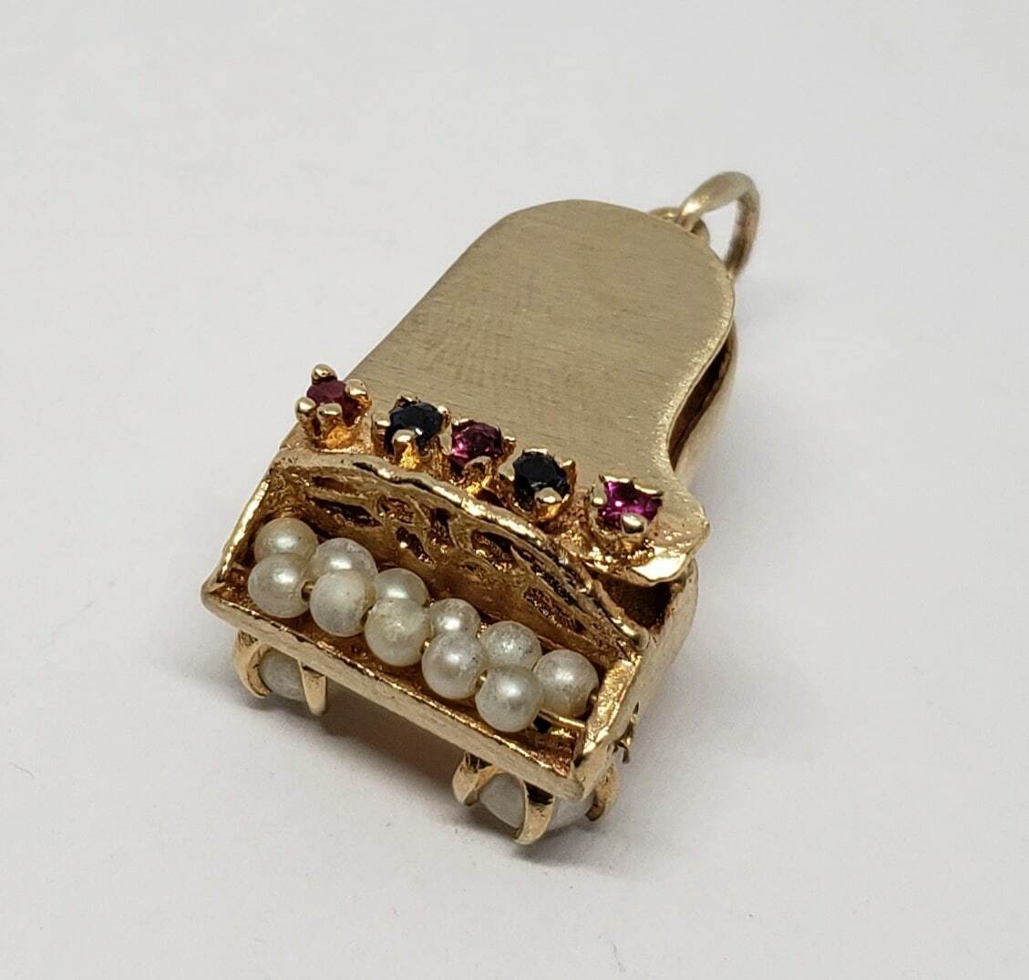 Gold piano charm with colorful gemstones.