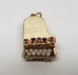 Gold piano charm with gemstones and pearls.