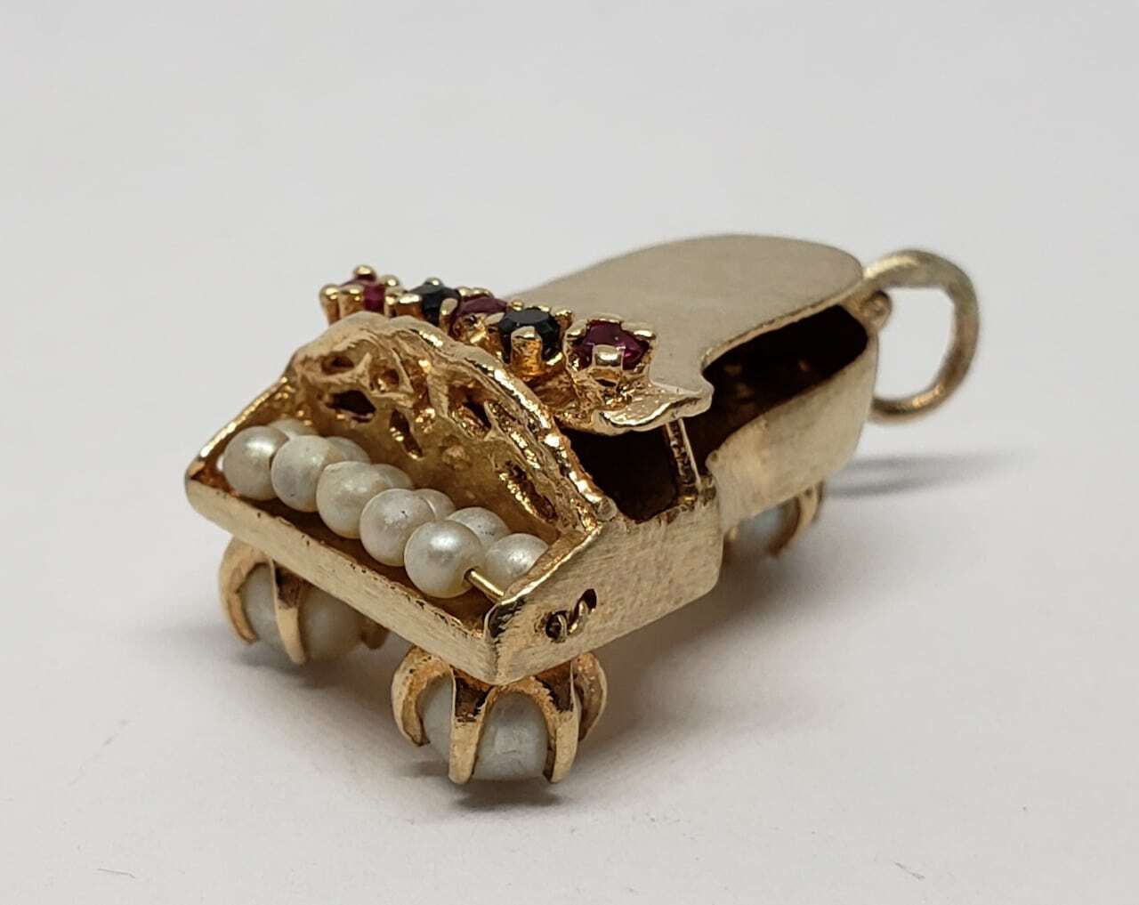 Gold piano charm with pearl keys.