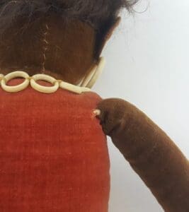 Vintage doll with red dress and necklace.