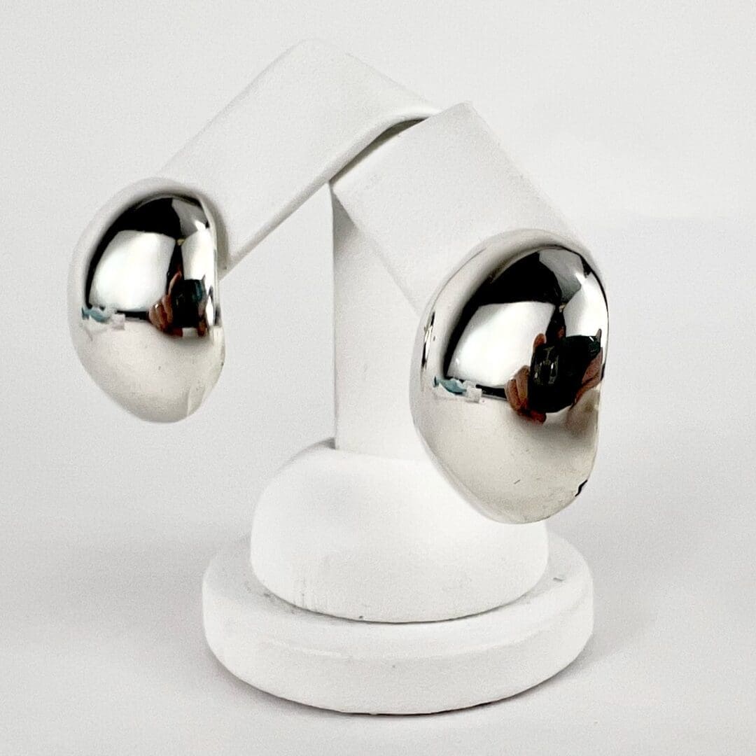 Silver reflective sculpture on white pedestal.