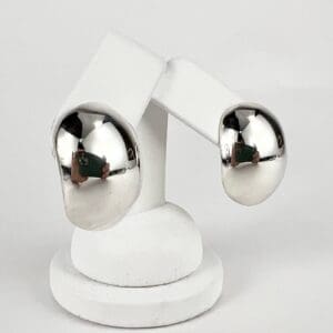 Silver hoop earrings on white display stand.