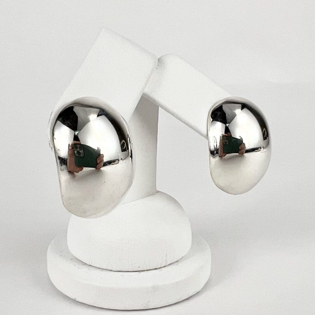Silver hoop earrings on white display stand.