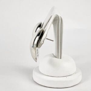 Silver earrings on a white display stand.