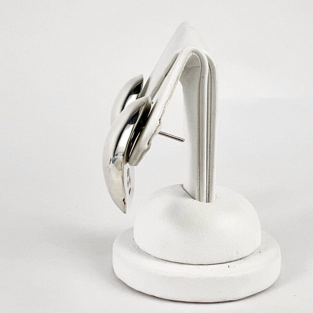 Silver earrings on a white display stand.