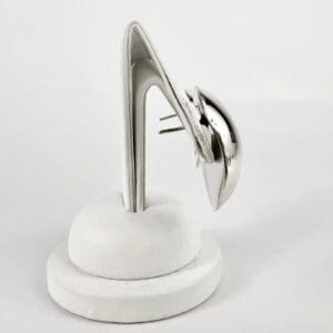 Abstract silver sculpture on white stand.