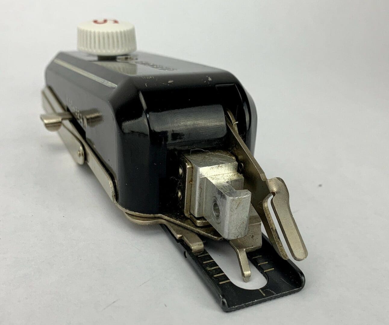 Vintage sewing machine attachment with metal components.